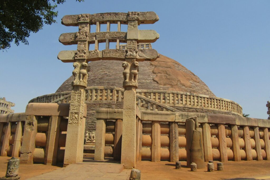 Panoramic view of the Great Stupa at Sanchi, one of India's oldest Buddhist monuments, against a clear blue sky.