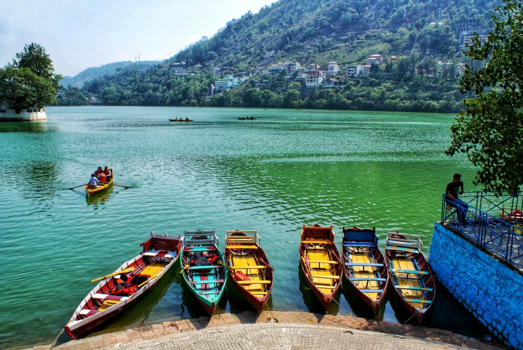 Beautiful view of Bhimtal Lake near Nainital, Uttarakhand, with colorful boats on the water and green mountains in the background.