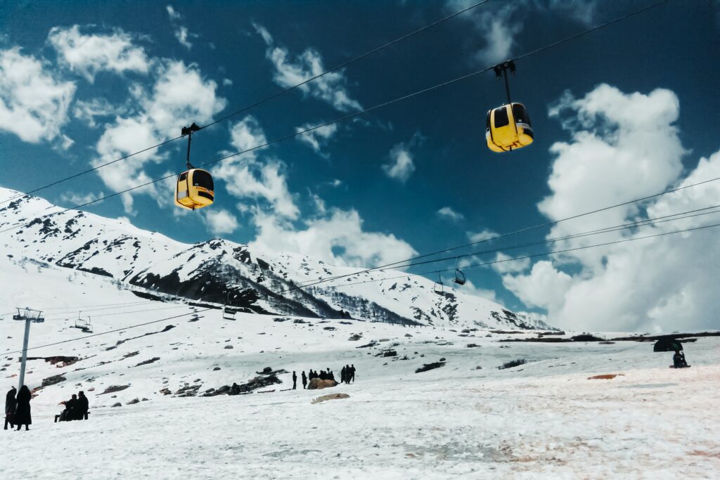 Tourists riding the Gulmarg Gondola cable car over snowy Himalayan peaks in Kashmir