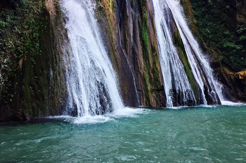 Tourists enjoying Kempty Falls Mussoorie, a multi-level waterfall with pools in the green hills