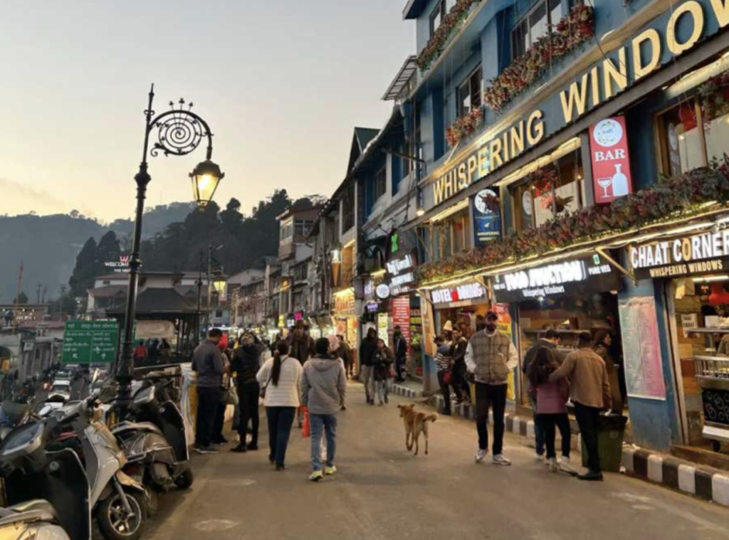 Bustling Mall Road in Mussoorie with people shopping, colonial architecture, and mountain backdrop