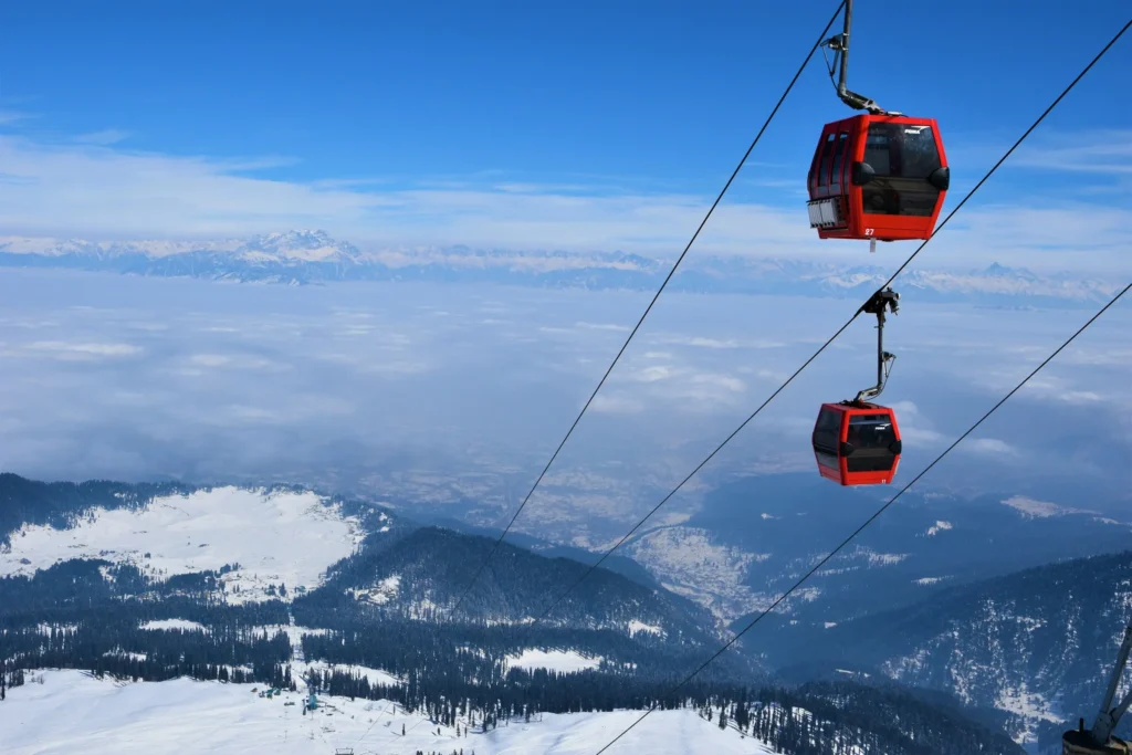 Tourist couple enjoying Gondola cable car ride in Gulmarg with snowy peaks