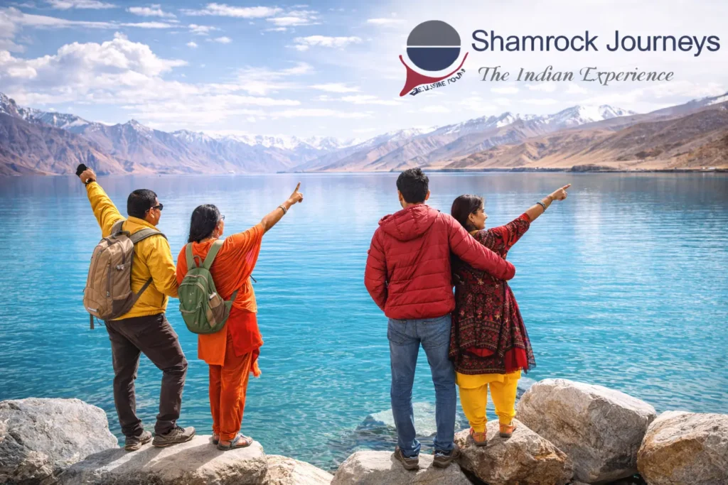 Travelers enjoying the stunning blue waters of Pangong Lake on a Ladakh tour package.