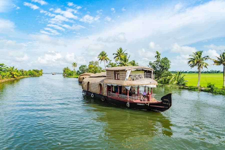 Traditional Kerala houseboat sailing through serene palm-fringed backwaters, a relaxing South India tour experience